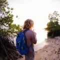 Seorang backpacker pemula Indonesia membawa ransel besar menikmati pemandangan alam indah